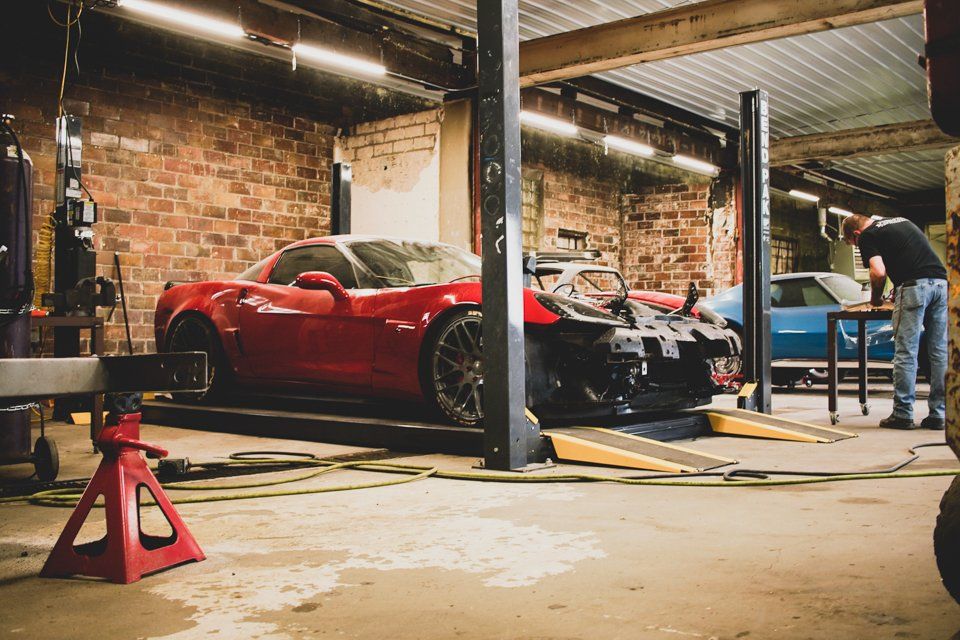 red corvette in service bay with hood and fender removed