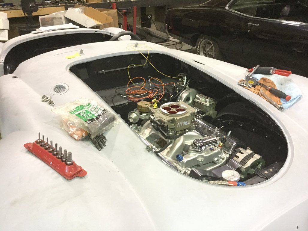 car hood removed and wires and engine exposed