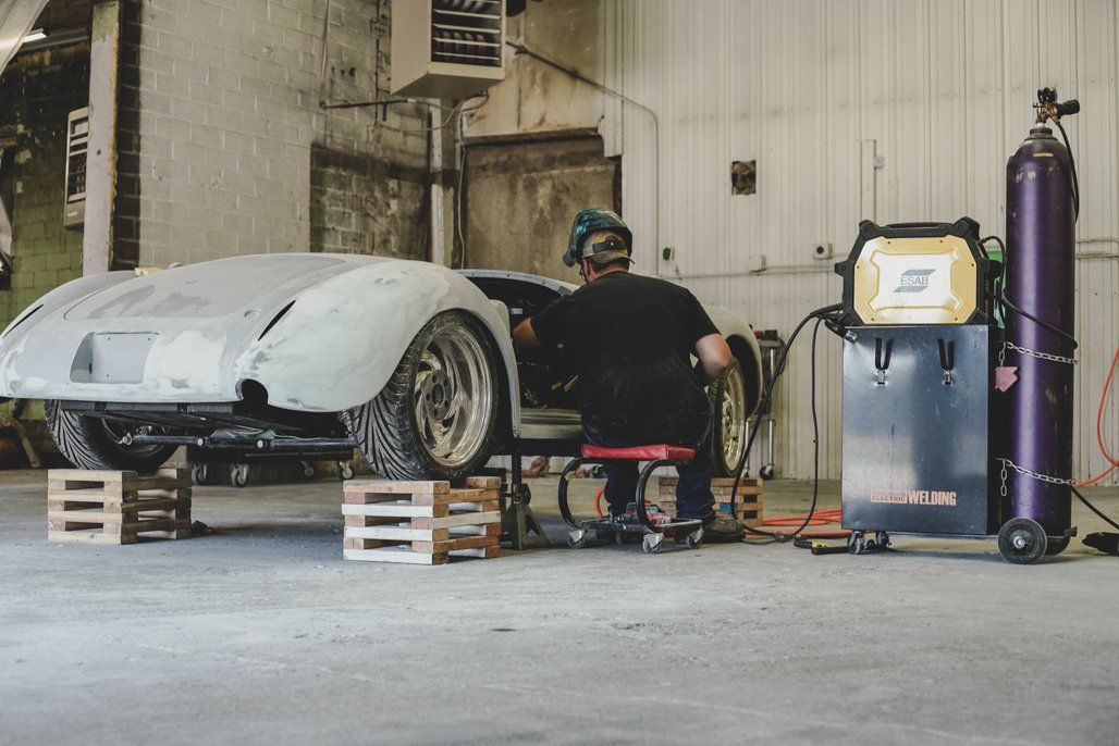 car suspended on crates with worker welding parts