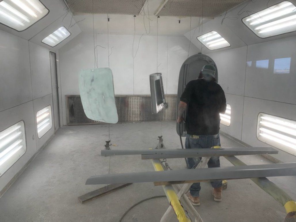 worker painting car part in paint room