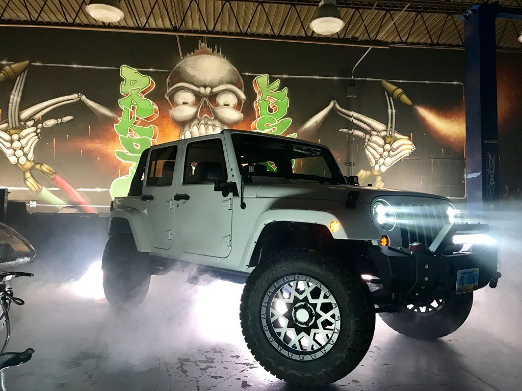 customized jeep with fog and lights indoors inside dakota kustomz garage with graffiti art in background