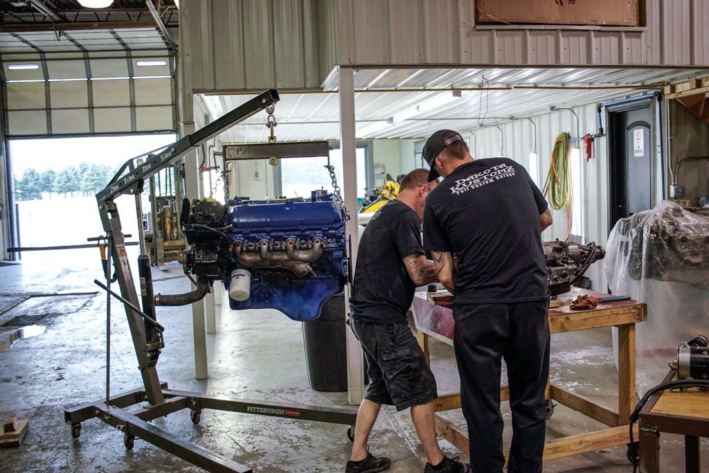 suspended engine and mechanics discussing plans