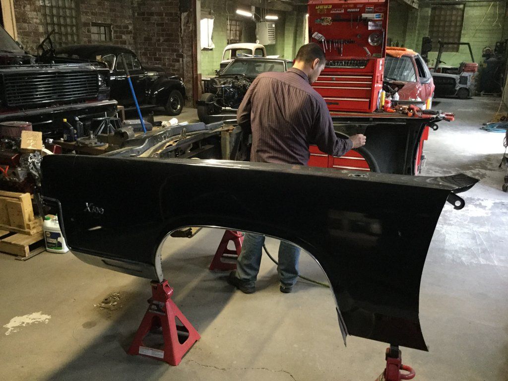 mechanic doing detail work on inside of suspended car frame