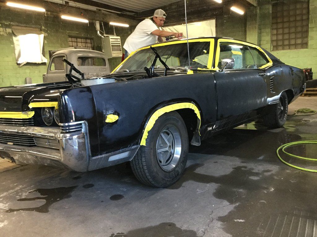 mechanic detailing on car with yellow tape