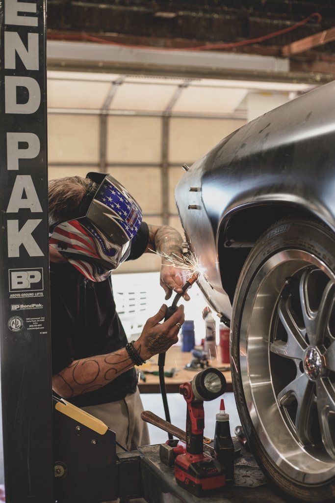 Garage worker welding a custom car's fender