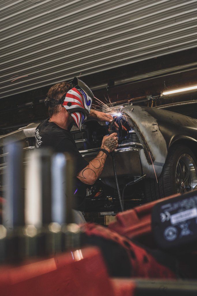 mechanic wearing american flag mask detailing rear fender