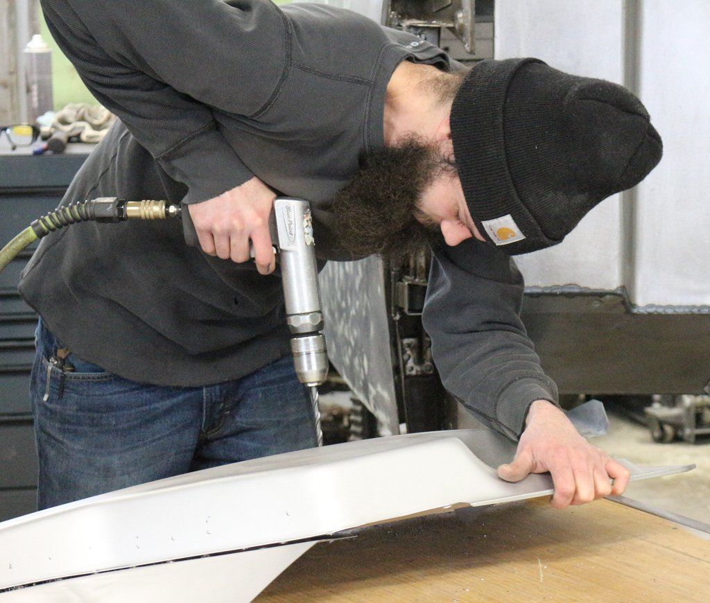 close up of mechanic using drill on truck parts