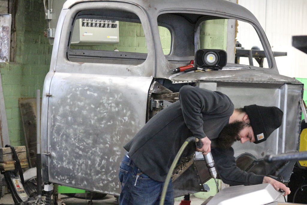 mechanic using drill on truck part