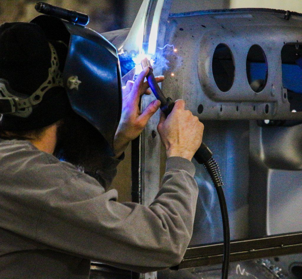 mechanic wearing welding mask and using a torch on truck frame