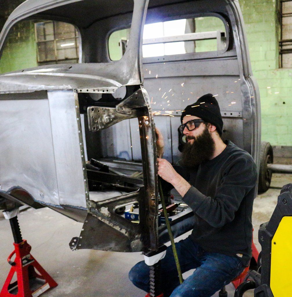 mechanic performing detailed work on truck frame making sparks