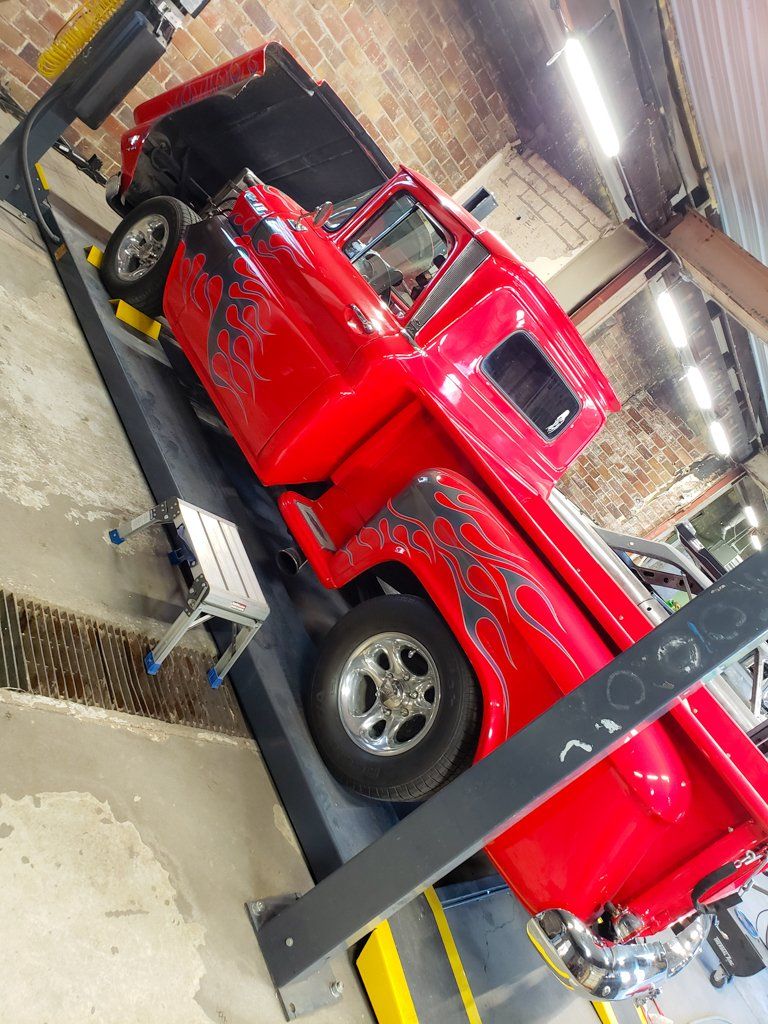 side view of 1962 red customized truck with grey flames on service bay