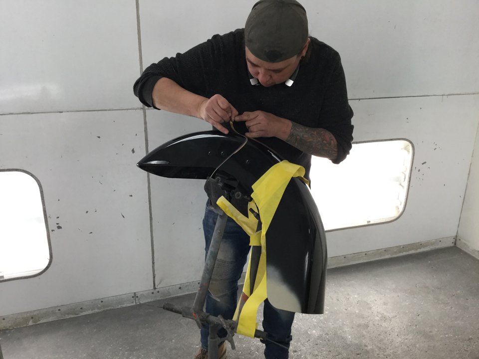 painter applying pin-striping to isolated motorcycle part