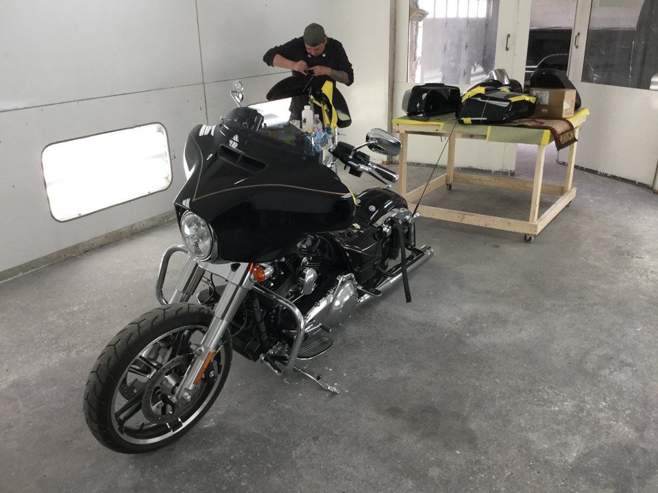 painter adding customization to motorcycle part behind black motorcycle