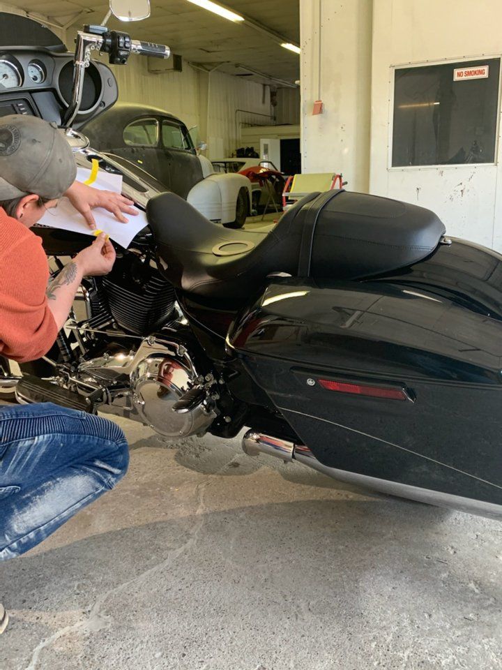 painter applying custom pinstriping to black motorcycle