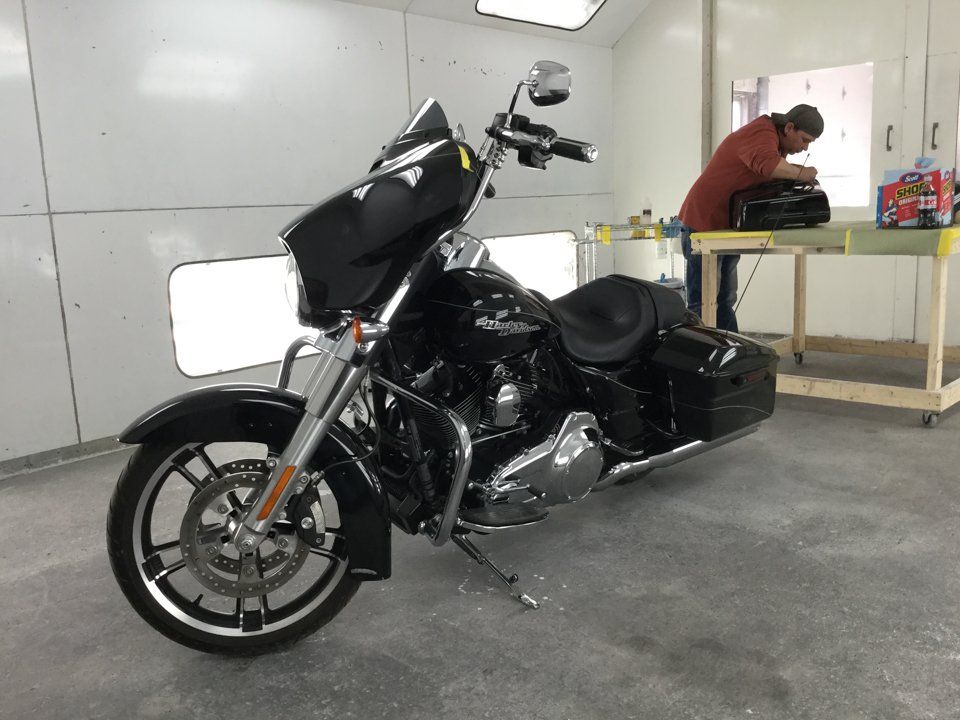 side view of black motorcycle with worker working  in the background