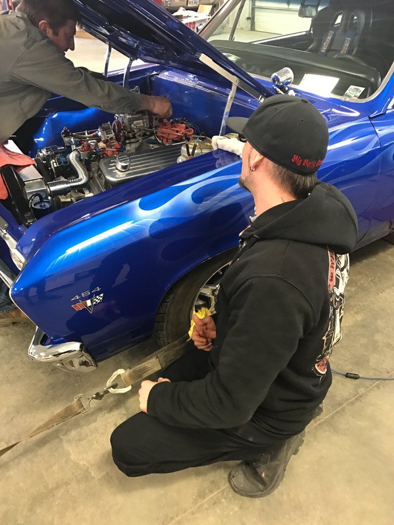 mechanic sitting next to car looking at engine