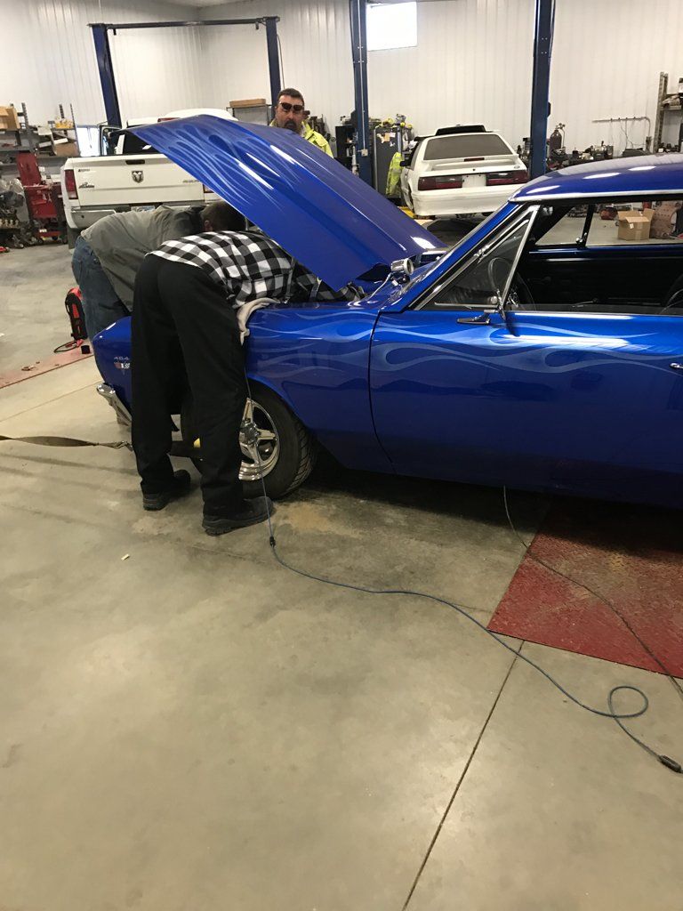 multiple mechanics looking inside of car hood