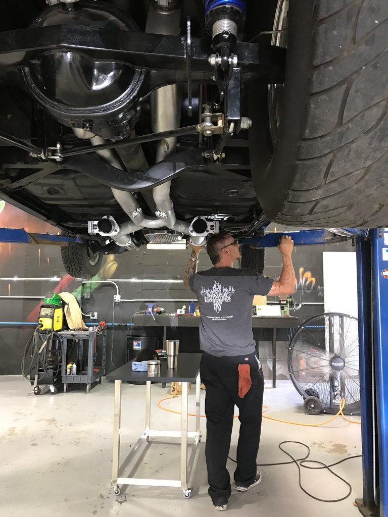 car lifted on service bay with mechanic working underneath