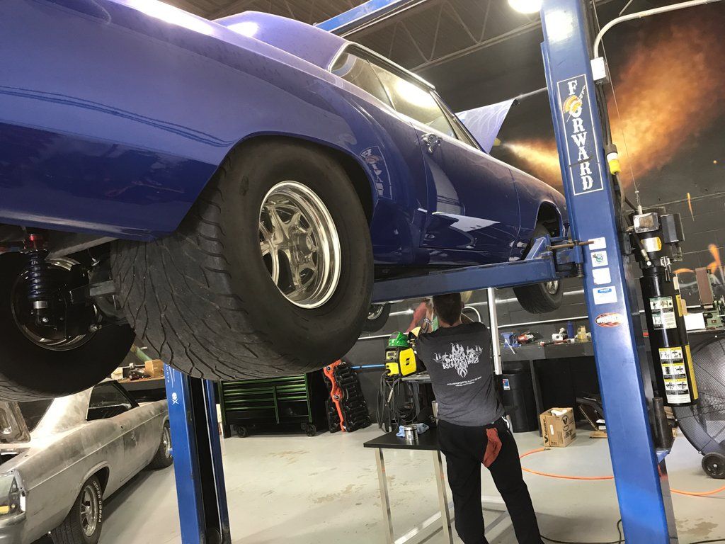 car lifted on service bay with mechanic working underneath
