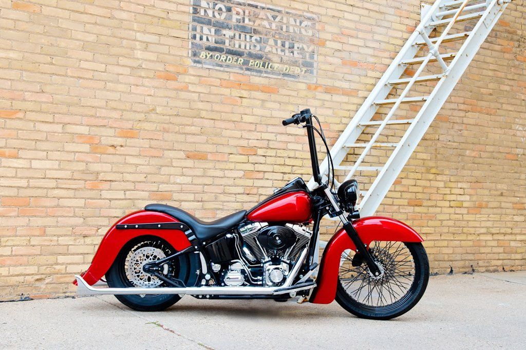 customized red and black chopper side view outdoors next t to brick wall and stairs
