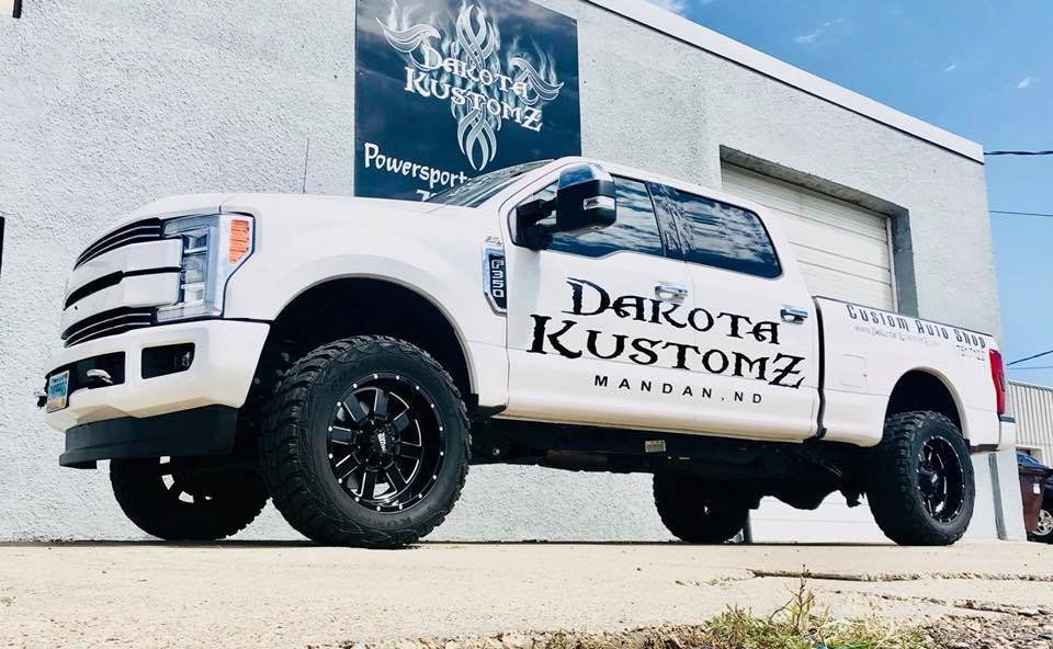 customized white ford f350 diesel pickup truck in front of dakota kustomz garage