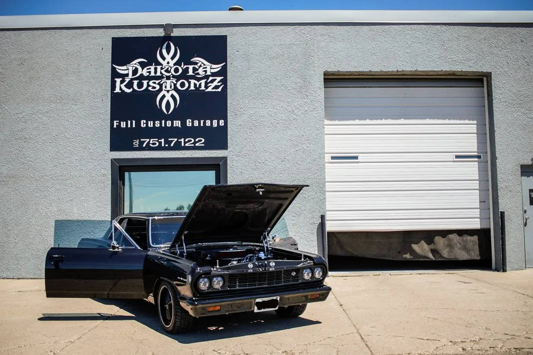 customized black 1964 chevy chevelle with dakota kustomz building in background