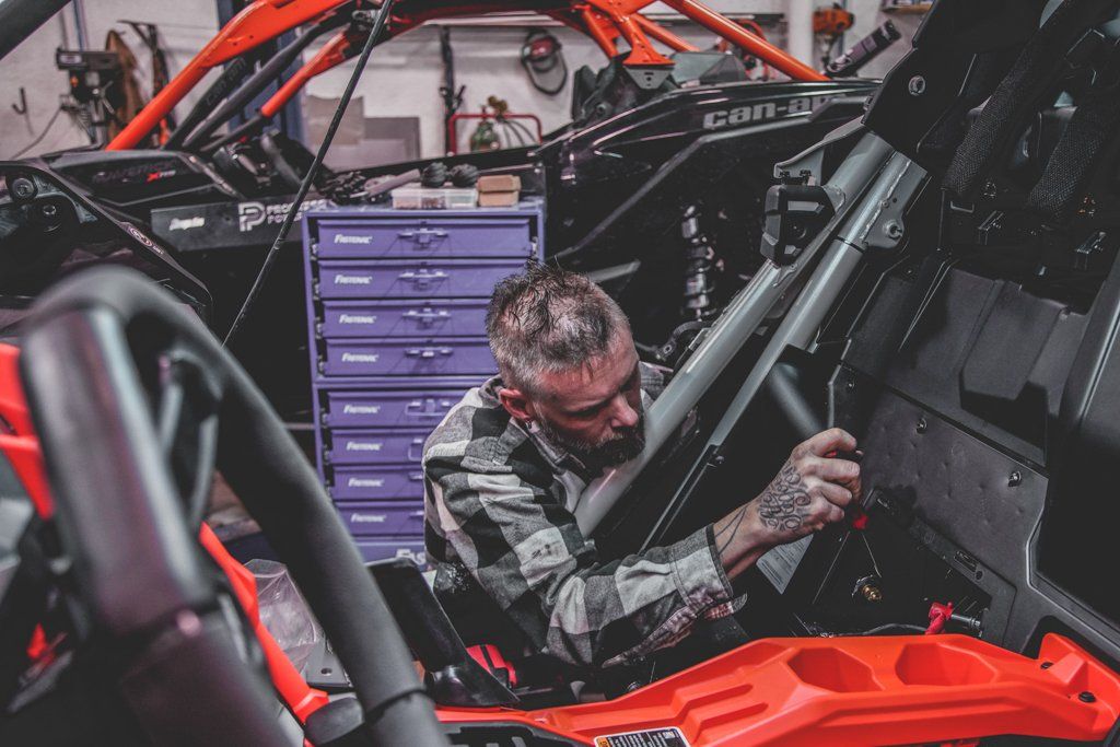 mechanic adjusting something in the interior of the custom 2021 red and black maverick
