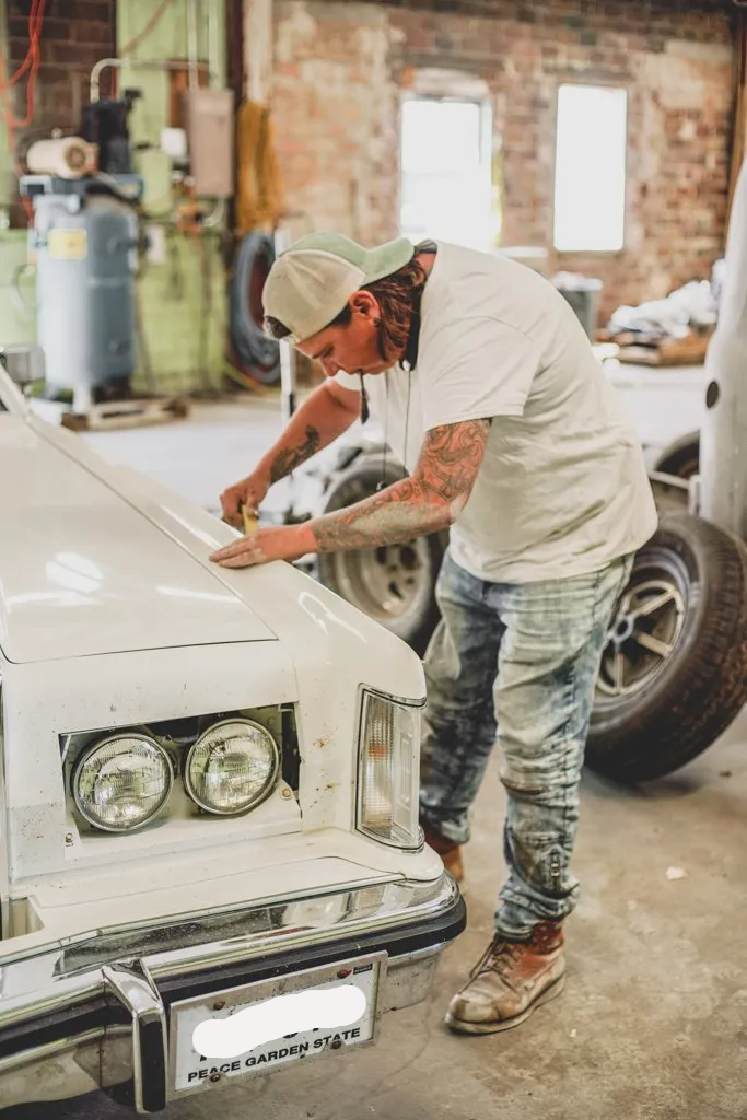 painter applying pinstriping to white lincoln