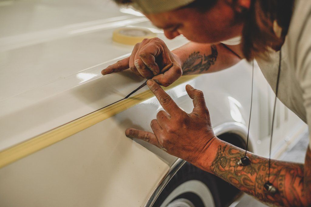 Painter painting custom pinstripe on white car