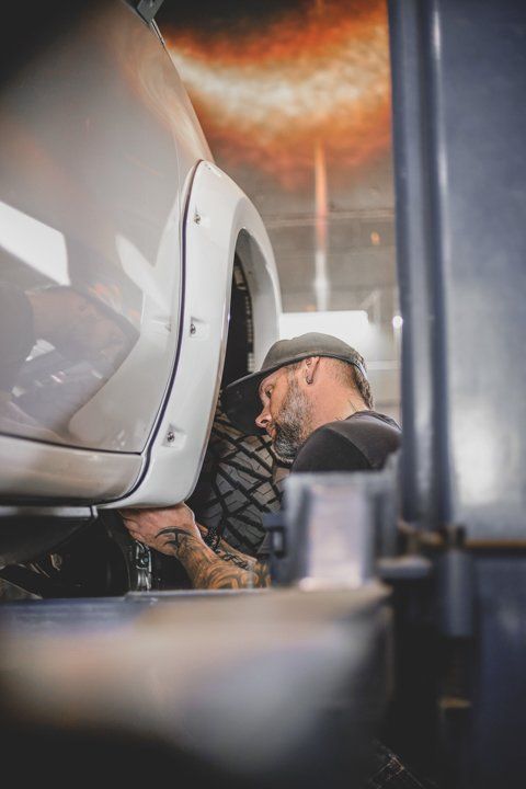 Dakota Kustomz mechanic inspecting wheels in white custom car