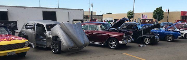 outdoor lineup of custom hotrods in front of Dakota Kustomz garage