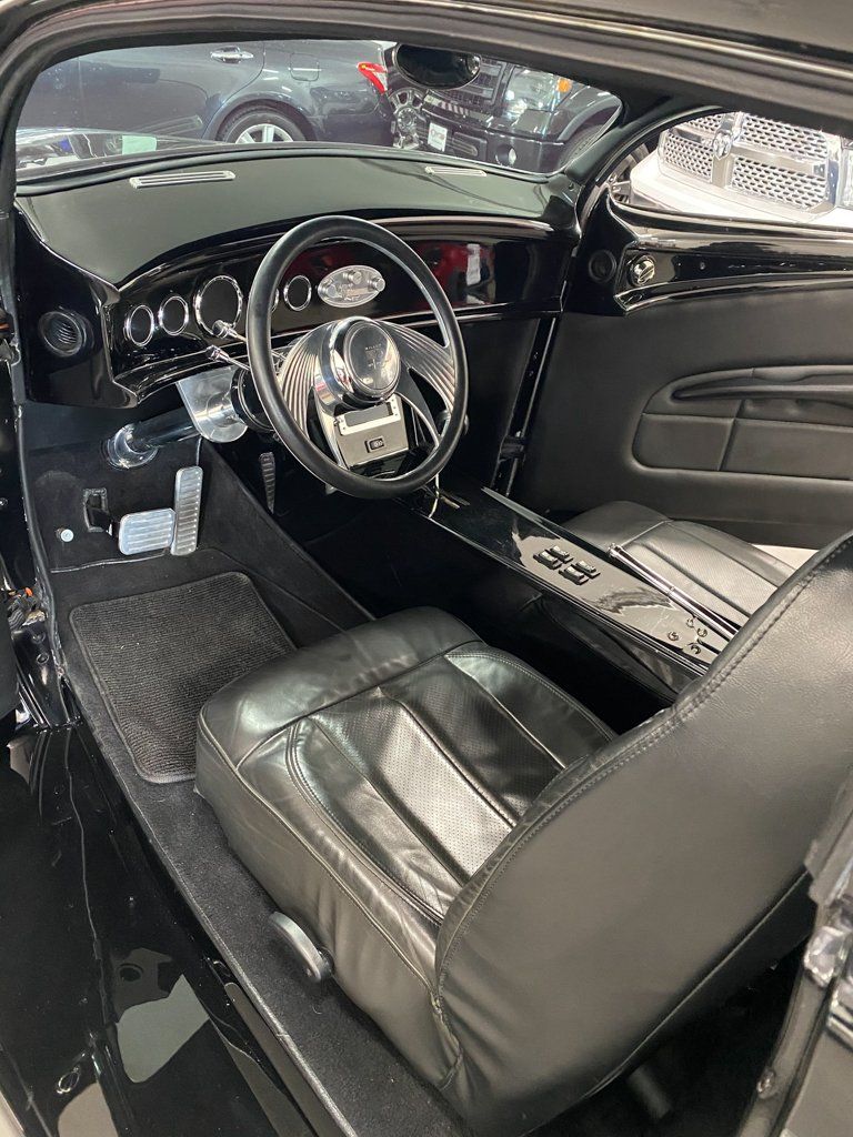 interior shot of steering wheel and driver seat for custom black 1937 ford tudor hot rod