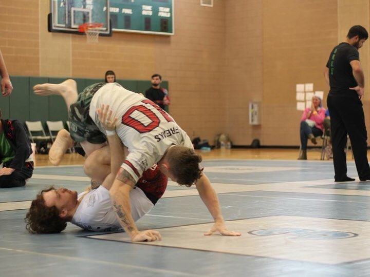 Two men are wrestling in a gym and one has the number 10 on his shirt