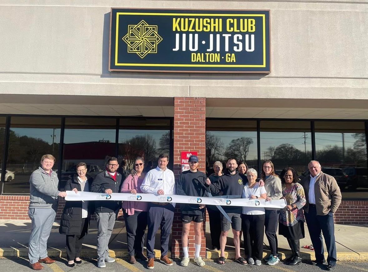 A group of people are standing in front of a building that says kuzushi club jiu-jitsu
