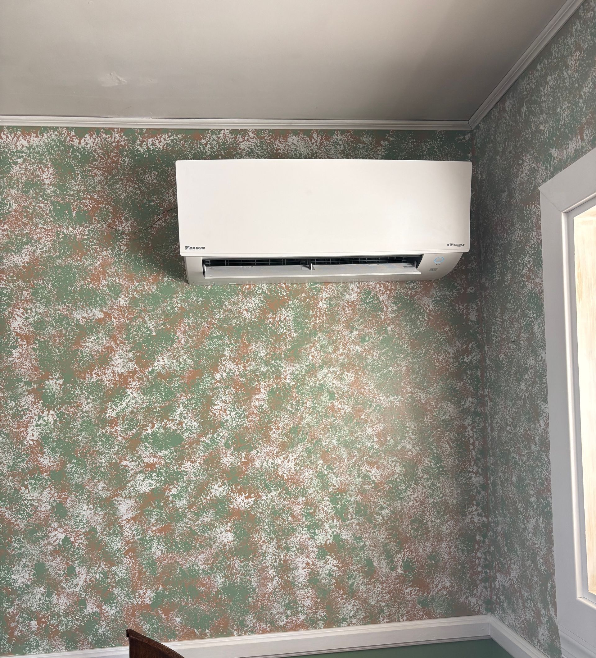A room with a table and chairs and a wall mounted air conditioner.