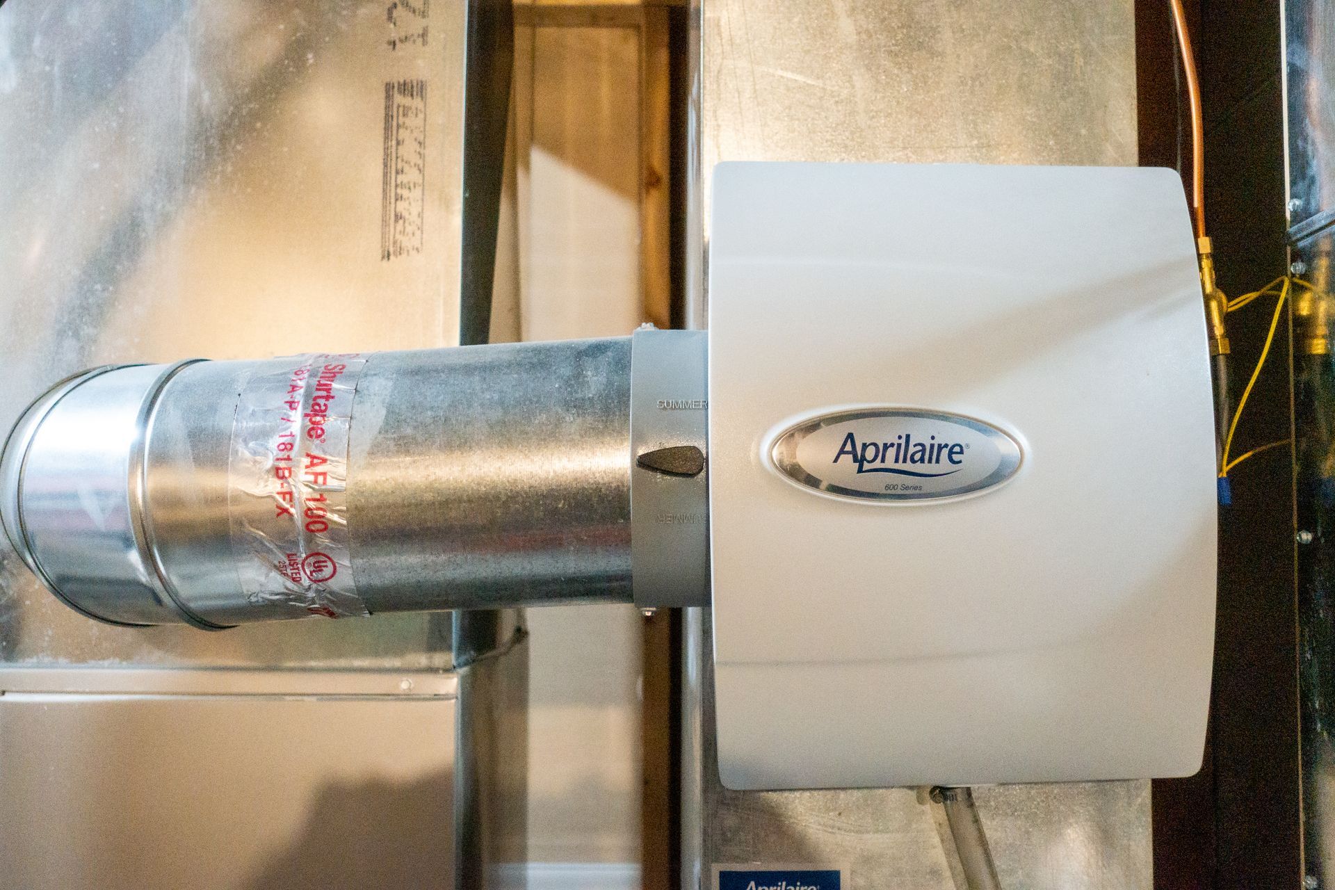 A white air conditioner is sitting on top of a metal pipe.