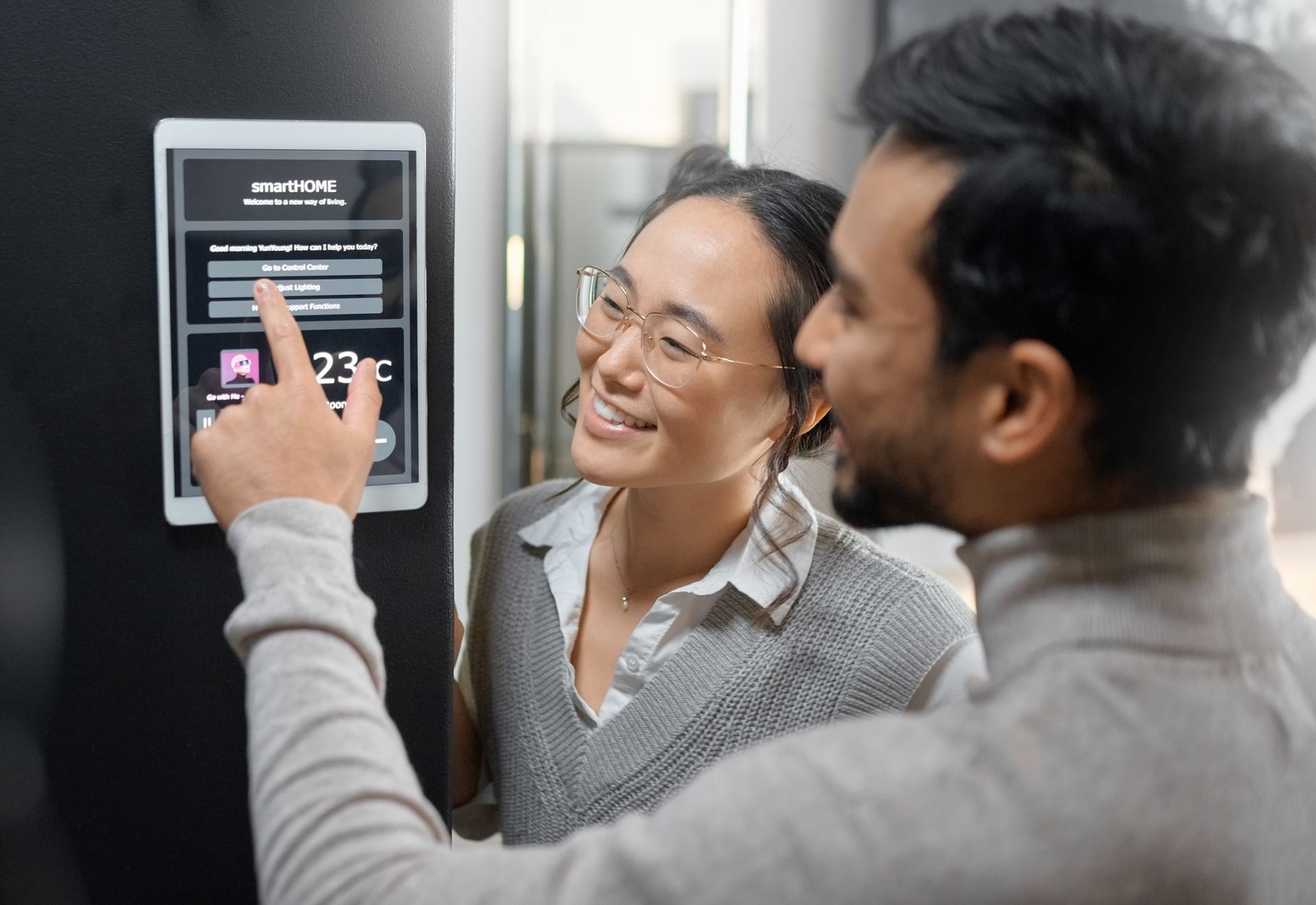 A man and a woman are looking at a thermostat.