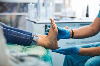 A doctor is holding a model of a foot in his hands.