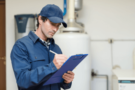 Picture of a plumber in a blue cap writing on a clipboard.