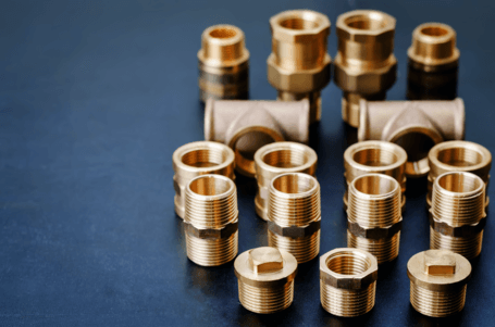 Picture of gold plumbing parts on a blue surface.