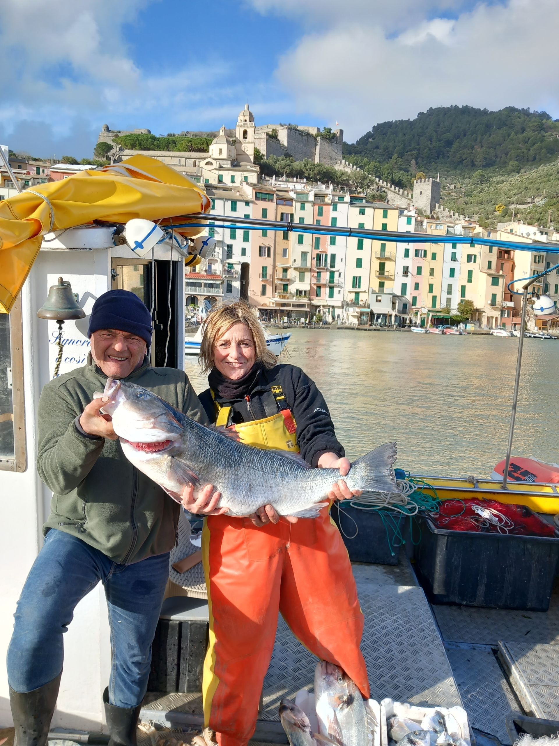 Un uomo e una donna tengono in mano un grosso pesce su una barca.