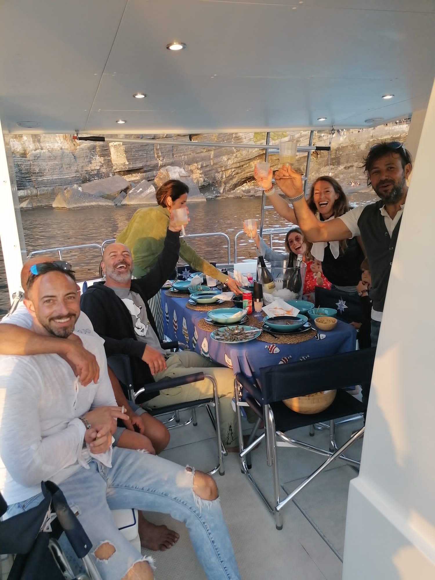 Un gruppo di persone è seduto attorno a un tavolo su una barca.