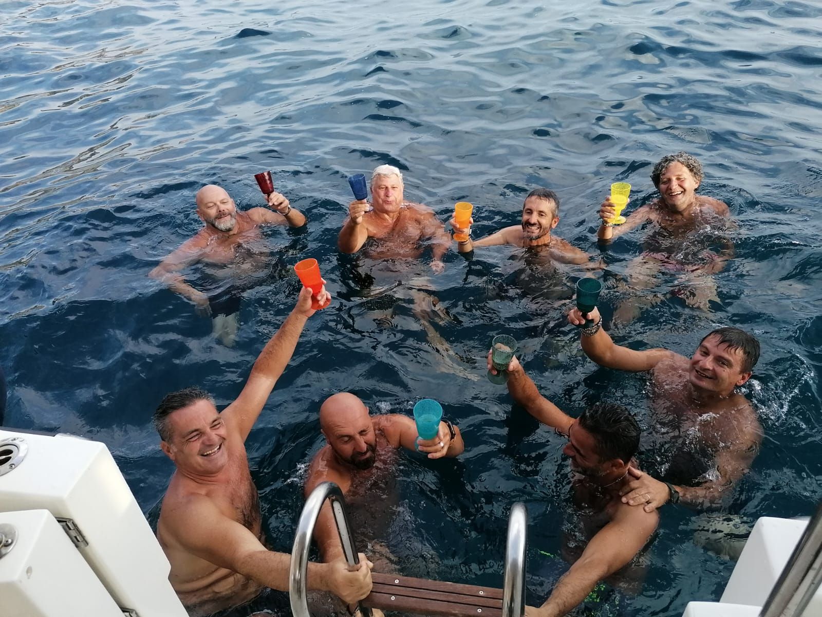 Un gruppo di persone è seduto nell'acqua tenendo in mano dei bicchieri