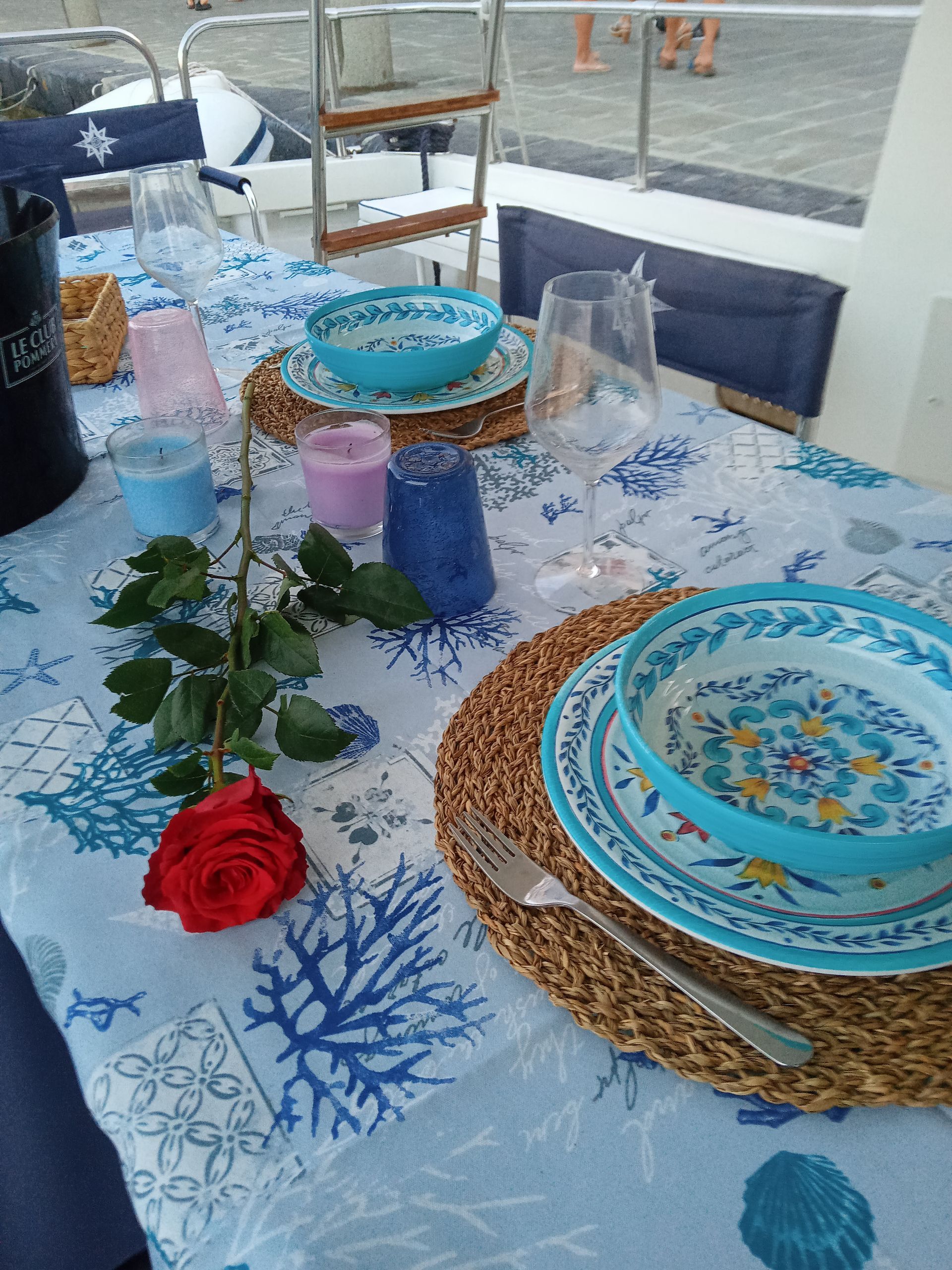 Un tavolo con piatti, bicchieri e una rosa sopra