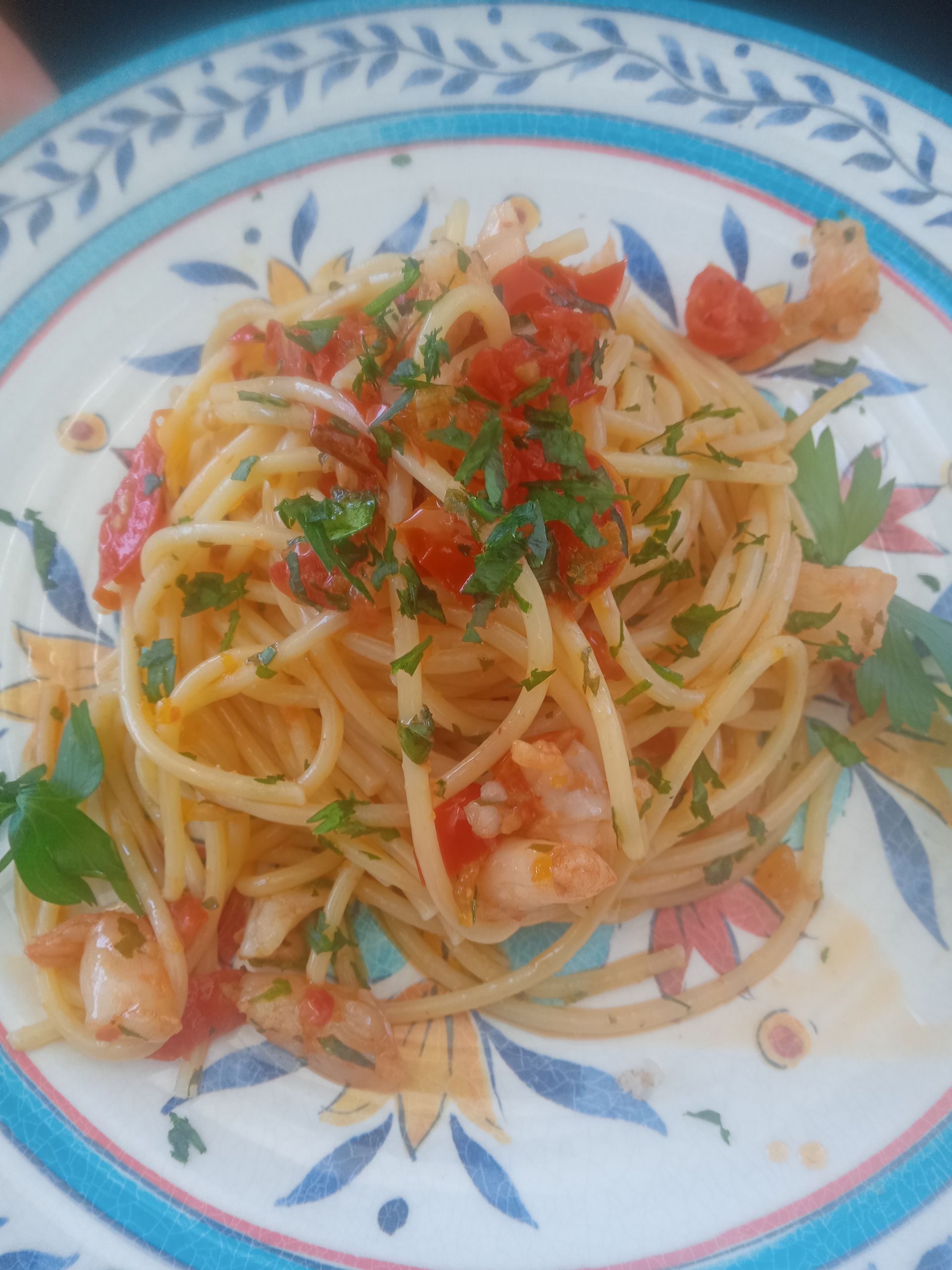 Un piatto di spaghetti con gamberi e salsa di pomodoro su un tavolo.