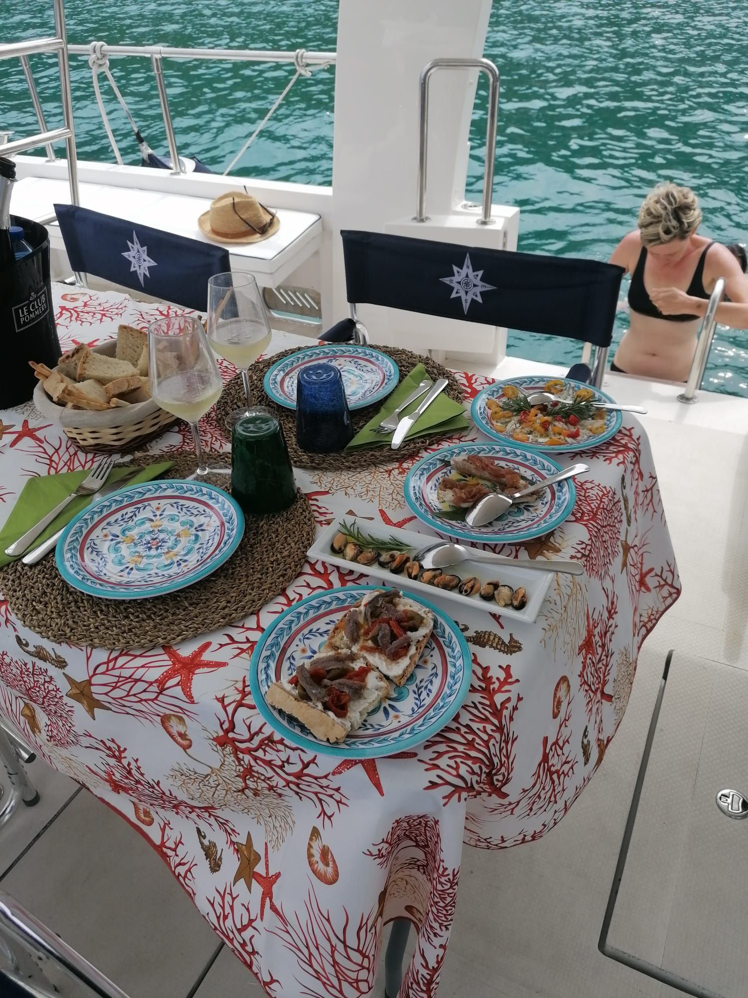 Un tavolo con piatti di cibo e vino su una barca.