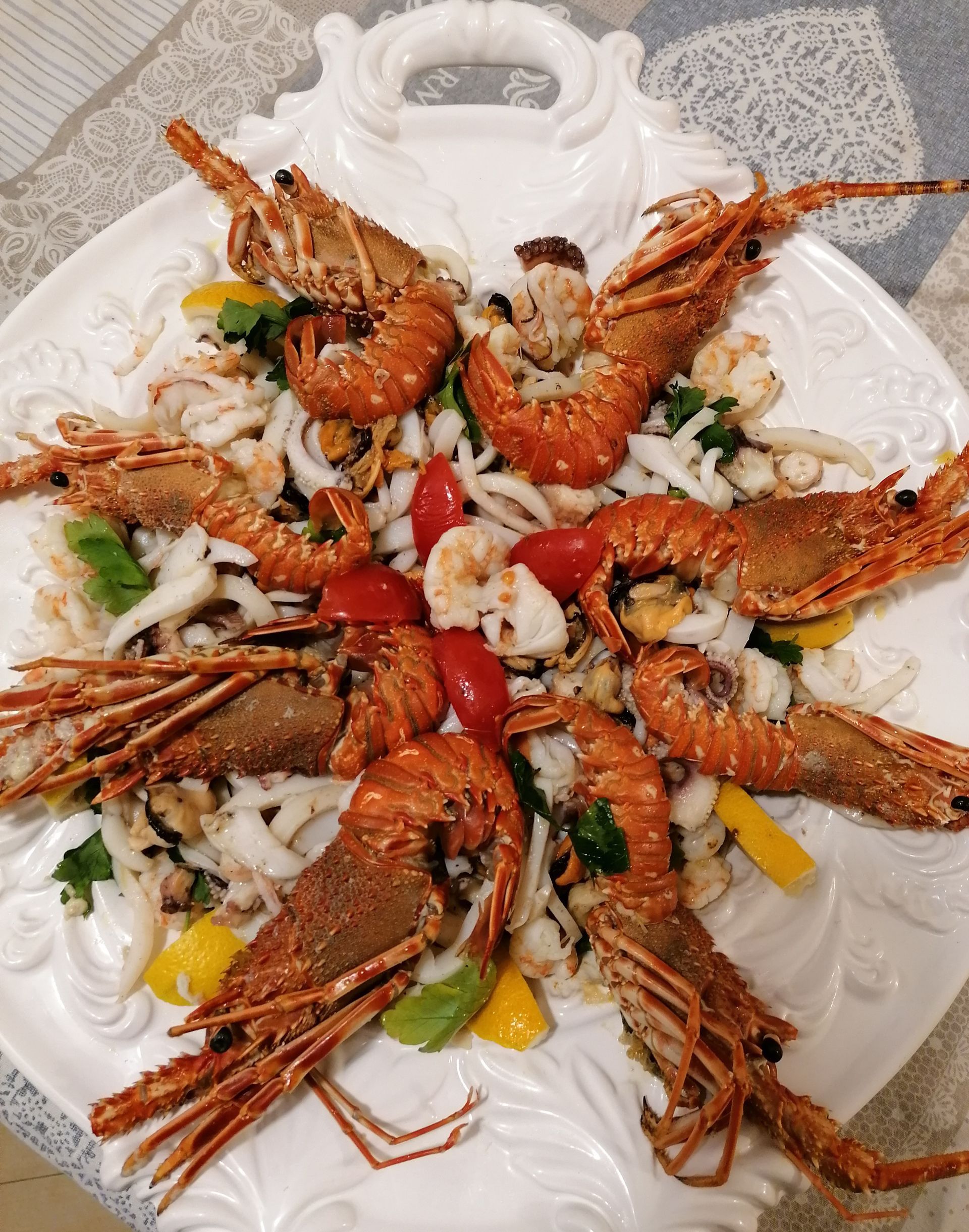 Un piatto bianco con sopra gamberi e verdure su un tavolo