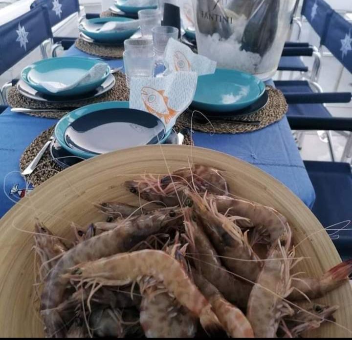 Un piatto di gamberi è appoggiato su un tavolo accanto a un secchiello per martini