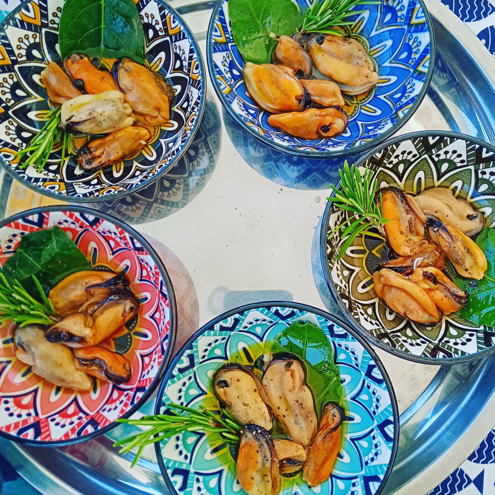 Quattro piatti di cibo con cozze e verdure su un vassoio