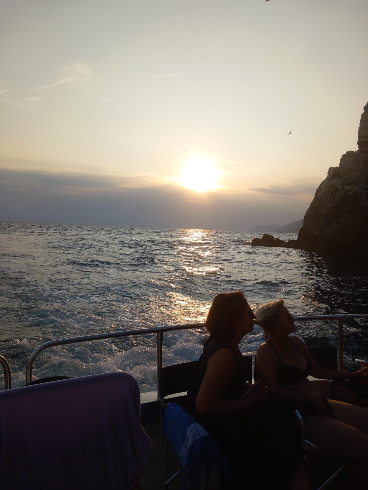 Due donne sono sedute su una barca nell'oceano al tramonto